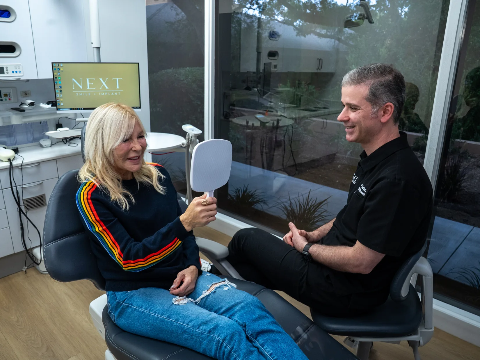 A Next Smile+Implant patient reviewing her smile in the mirror